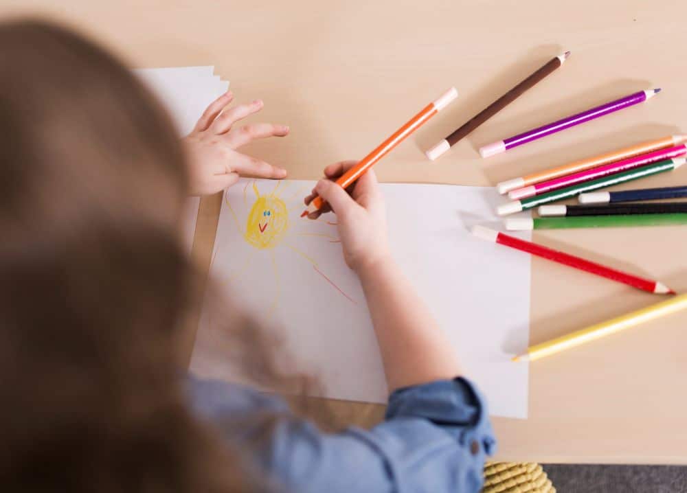 Criança desenhando e pintando em papel 