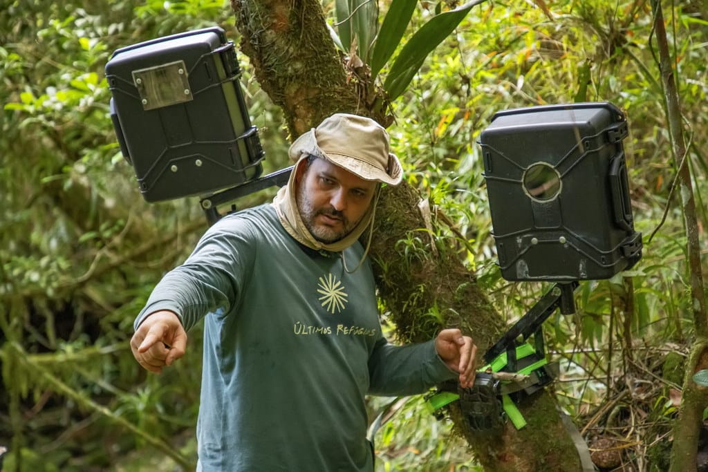 Fotógrafo instalando armadilha fotográfica em uma densa floresta para capturar imagens da vida selvagem.