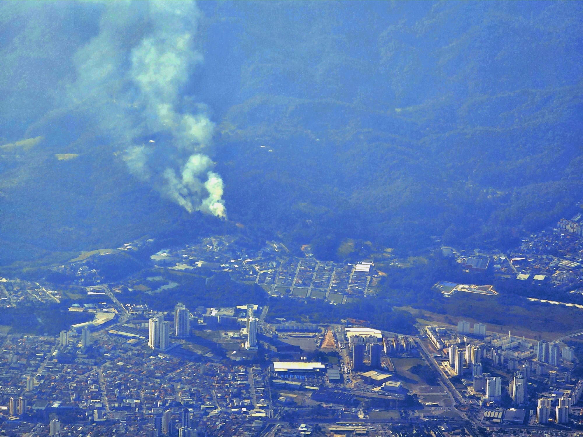 Fotografia aérea de focos de incêndio e densa camada de fumaça, vista da janela de um avião, durante o voo entre São Paulo e Espírito Santo