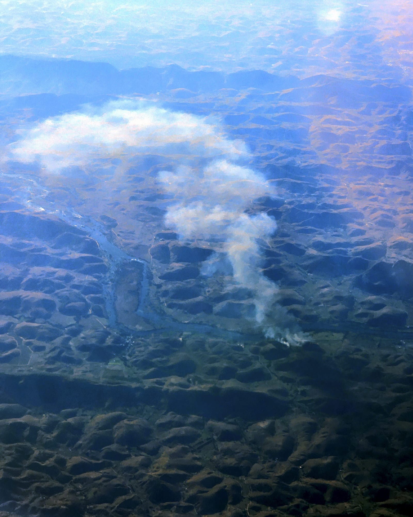 Texto Alternativo:** Fotografia aérea de focos de incêndio e densa camada de fumaça, vista da janela de um avião, durante o voo entre São Paulo e Espírito Santo.