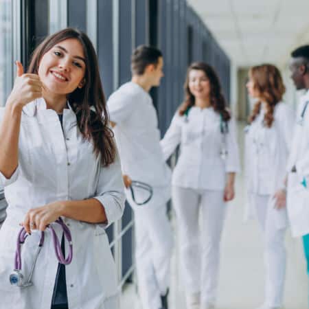 young-female-doctor-with-thumbs-up-gesture-standing-corridor-hospital