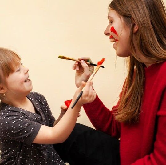 Criança e adulta brincando com pincel e tinta