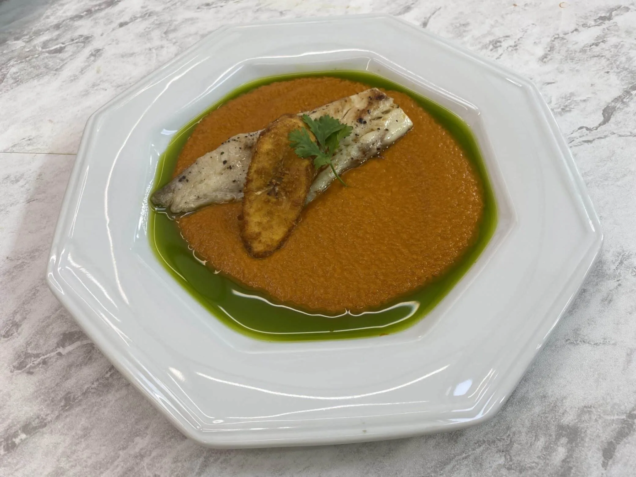 Velouté de moqueca com tilápia grelhada, banana crocante e azeite de coentro