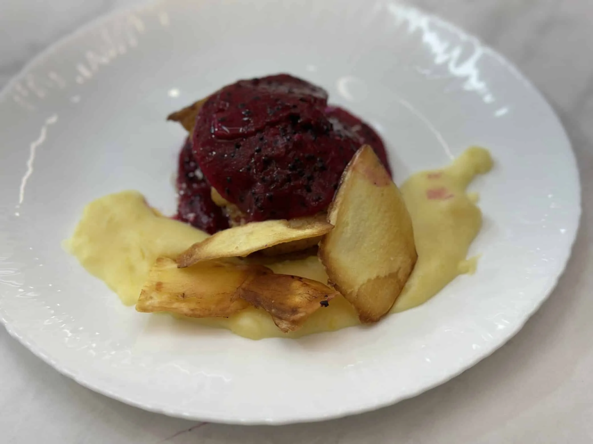 Ravioli recheado com sobrecoxa, purê de mandioca e crispe de mandioca